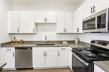 A modern kitchen with white cabinets and stainless steel appliances.